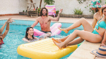 Young people hanging out by a pool with a big yellow float.