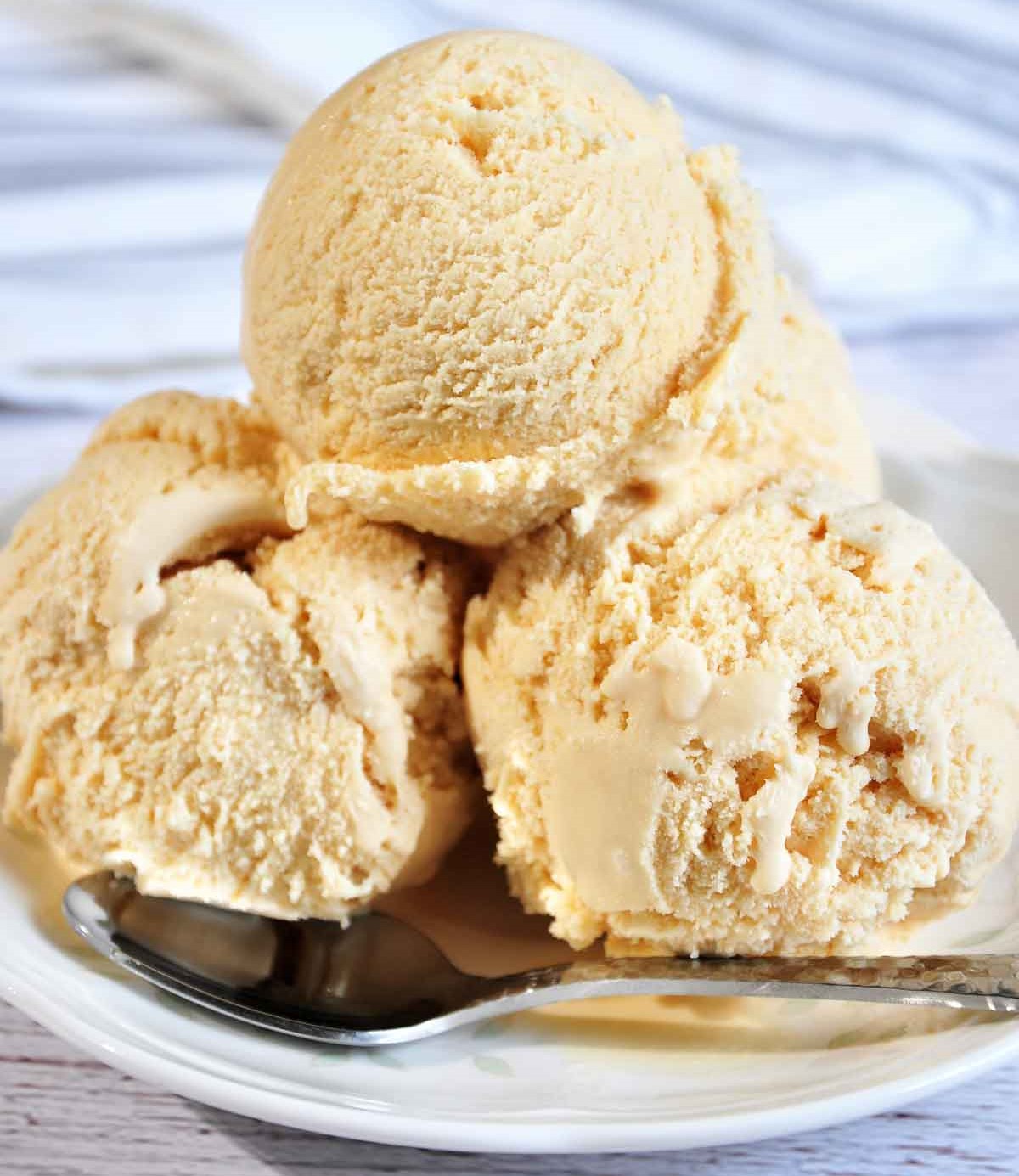 Three scoops of ice cream in a white plate with a spoon.