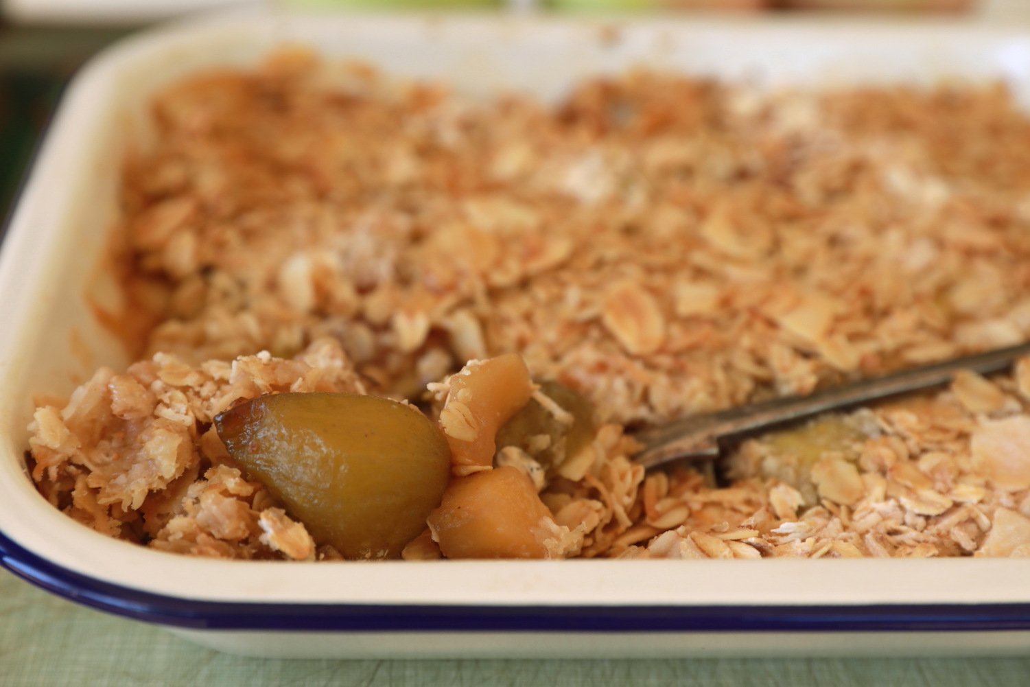 Fig and apple crumble in a white dish with a silver spoon.