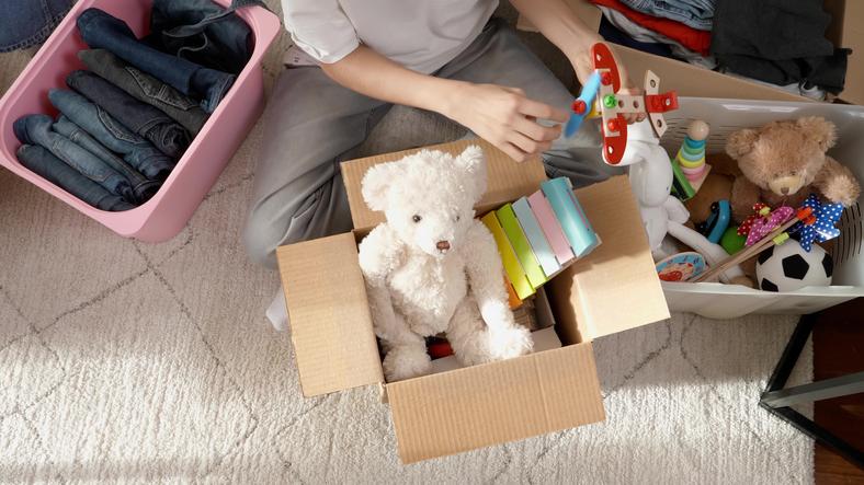 Boy preparing clothes and toys for charity donation as he is using decluttering tips.